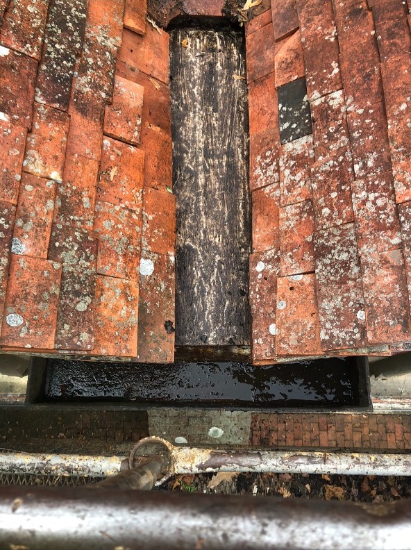 Roof valley gutter being cleaned to remove debris and improve water flow